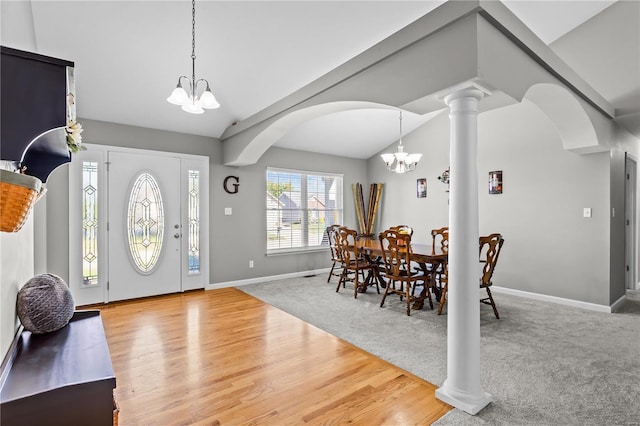 entryway featuring lofted ceiling, carpet flooring, wood finished floors, decorative columns, and an inviting chandelier