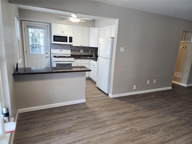 kitchen with sink, white appliances, white cabinetry, and kitchen peninsula