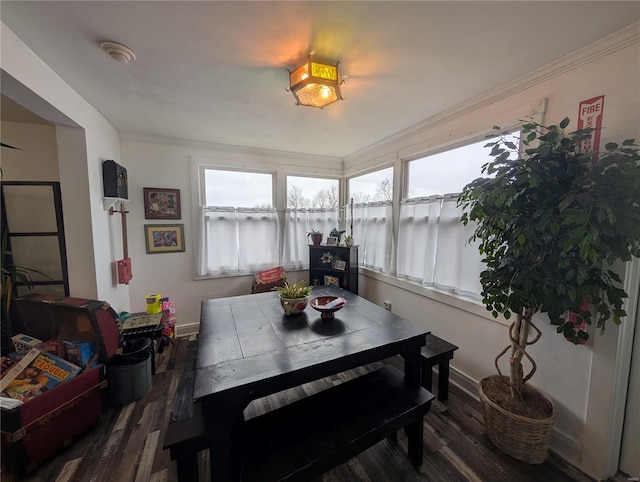 dining area with crown molding and dark wood-type flooring