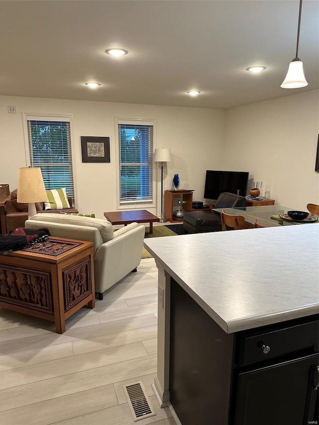 kitchen with a kitchen island, light wood-type flooring, and decorative light fixtures