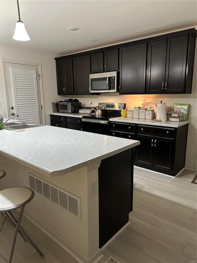 kitchen featuring sink, decorative light fixtures, a breakfast bar area, and appliances with stainless steel finishes