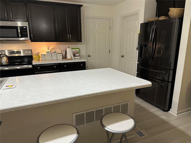 kitchen featuring appliances with stainless steel finishes, a breakfast bar, and light wood-type flooring