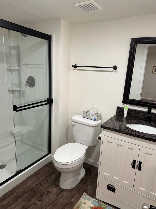 bathroom with vanity, wood-type flooring, a shower with door, and toilet