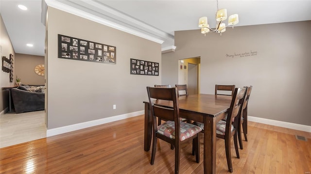 dining room featuring lofted ceiling, a chandelier, and light wood-type flooring