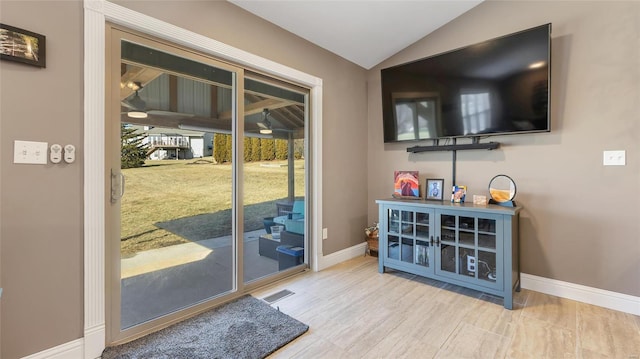 doorway with vaulted ceiling and light hardwood / wood-style floors