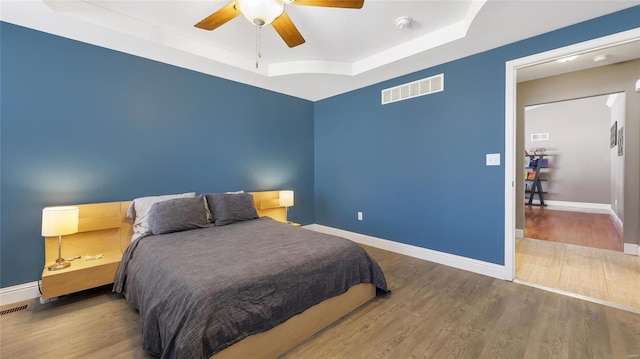 bedroom featuring a tray ceiling, ceiling fan, and hardwood / wood-style flooring