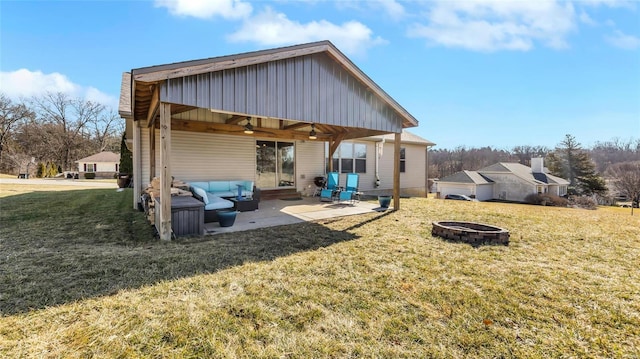 back of property with a yard, a patio, and an outdoor fire pit