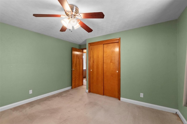 unfurnished bedroom with a closet, ceiling fan, light colored carpet, and a textured ceiling