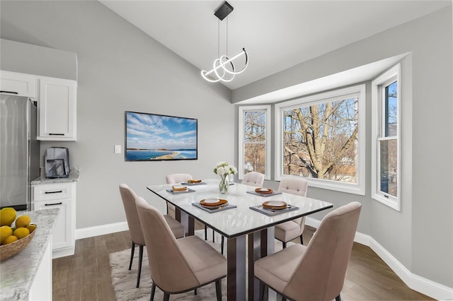 dining area with dark hardwood / wood-style flooring, vaulted ceiling, and a chandelier