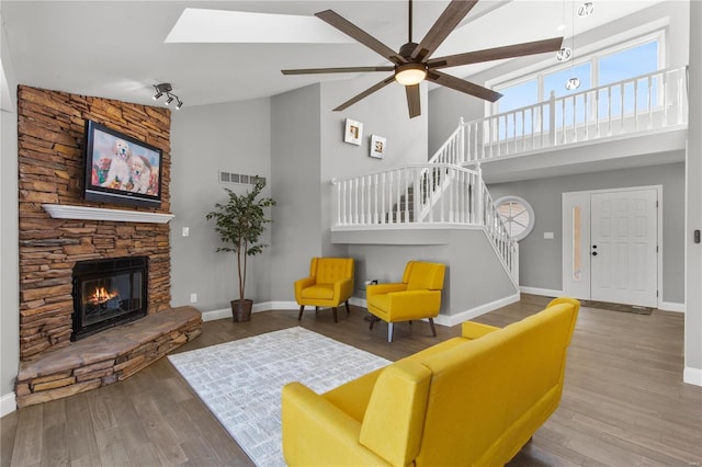 living room featuring ceiling fan, high vaulted ceiling, a fireplace, and hardwood / wood-style floors