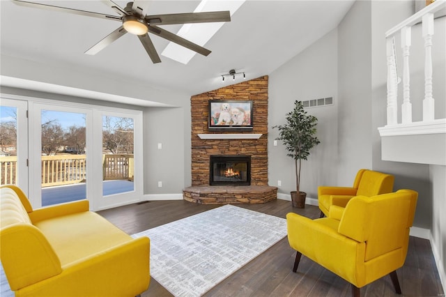 living room with a stone fireplace, vaulted ceiling, dark hardwood / wood-style floors, and ceiling fan