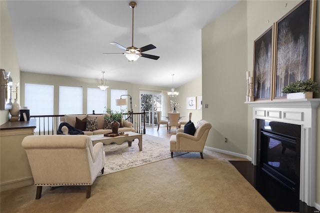 carpeted living room with ceiling fan with notable chandelier and vaulted ceiling