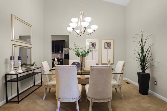 carpeted dining area with a towering ceiling and a chandelier