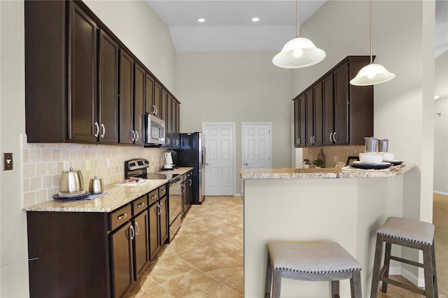 kitchen featuring tasteful backsplash, a breakfast bar, pendant lighting, and appliances with stainless steel finishes