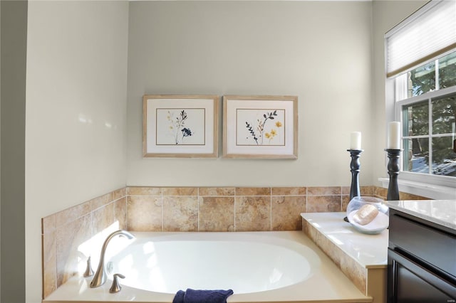 bathroom featuring tiled tub and vanity