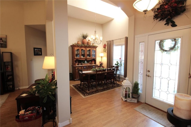 entryway with an inviting chandelier, a high ceiling, and light wood-type flooring