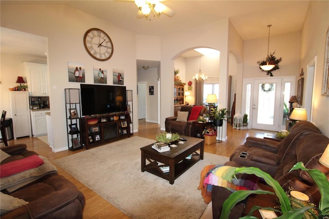 living room featuring an inviting chandelier, a towering ceiling, and light hardwood / wood-style floors