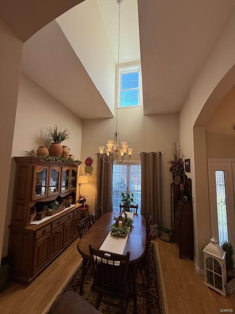 dining space with hardwood / wood-style floors, a notable chandelier, and a high ceiling