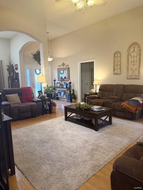 living room featuring a high ceiling, wood-type flooring, and ceiling fan