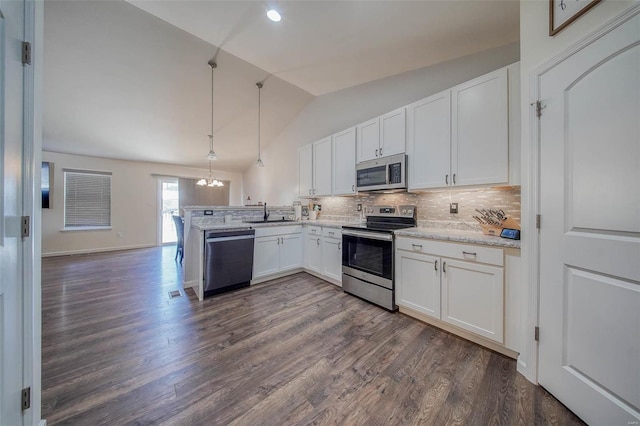 kitchen with pendant lighting, stainless steel appliances, white cabinets, vaulted ceiling, and kitchen peninsula