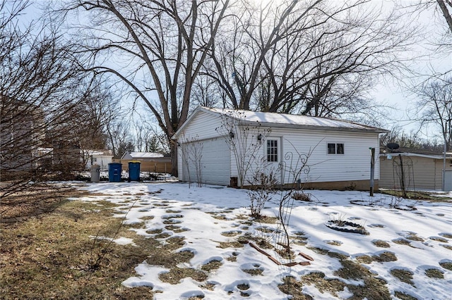 view of snowy exterior with a garage and an outdoor structure