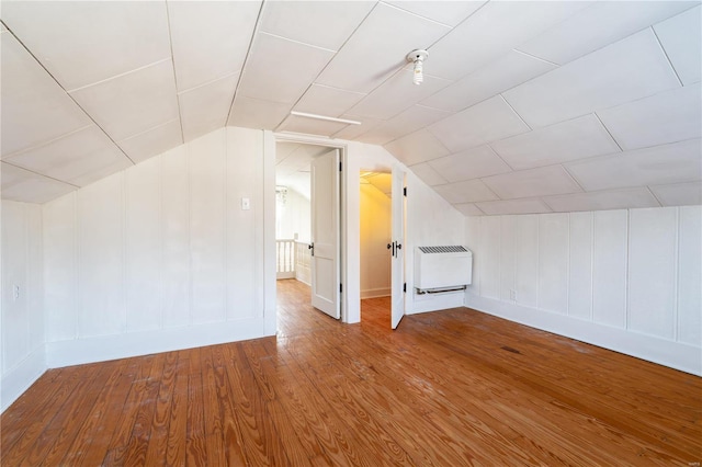 additional living space with lofted ceiling, hardwood / wood-style floors, and radiator