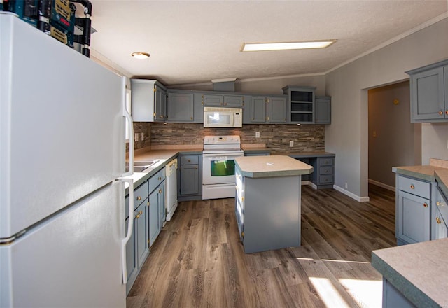 kitchen featuring gray cabinets, vaulted ceiling, a kitchen island, backsplash, and white appliances