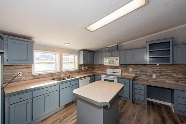 kitchen featuring lofted ceiling, blue cabinets, sink, a center island, and white appliances