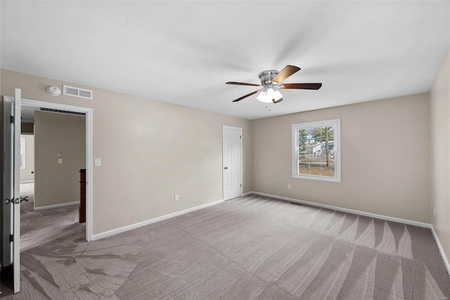 carpeted spare room featuring ceiling fan, visible vents, and baseboards