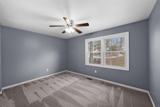 unfurnished room with carpet floors, visible vents, baseboards, and a ceiling fan