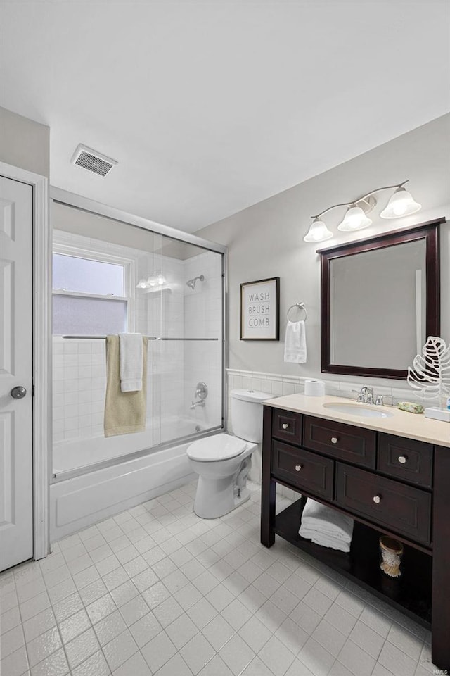 full bath featuring visible vents, shower / bath combination with glass door, vanity, and toilet