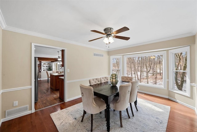 dining space with ornamental molding, visible vents, and wood finished floors