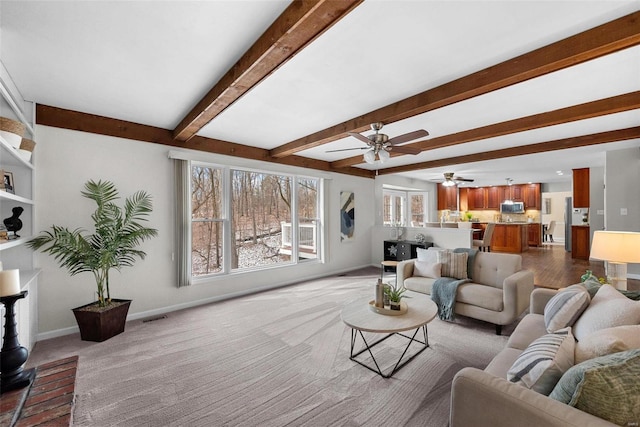 living room featuring carpet floors, beam ceiling, visible vents, ceiling fan, and baseboards