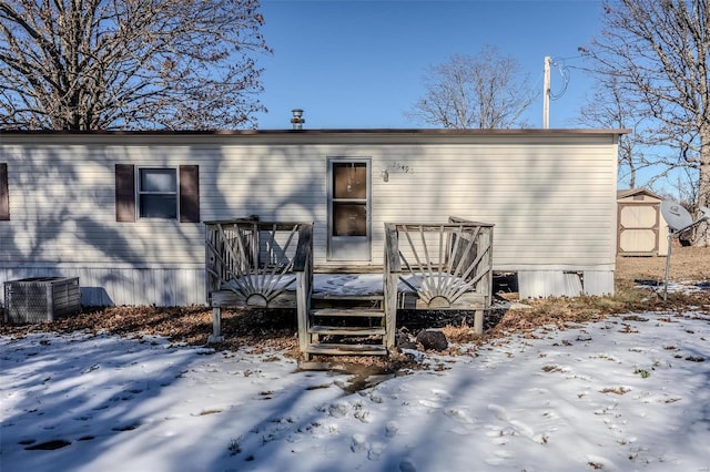 snow covered rear of property with cooling unit