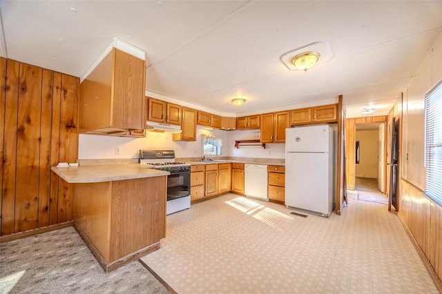 kitchen featuring kitchen peninsula, white appliances, and wooden walls