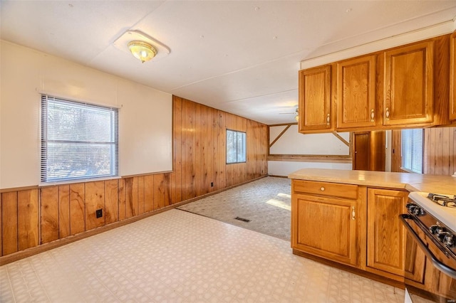 kitchen with white gas range, wooden walls, and a wealth of natural light