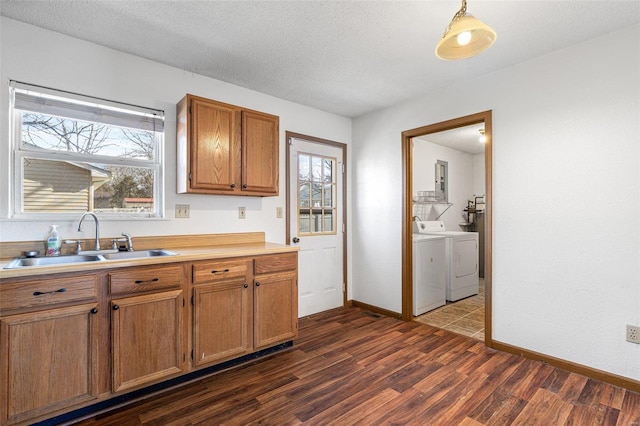 kitchen with sink, dark hardwood / wood-style floors, a textured ceiling, washing machine and clothes dryer, and decorative light fixtures