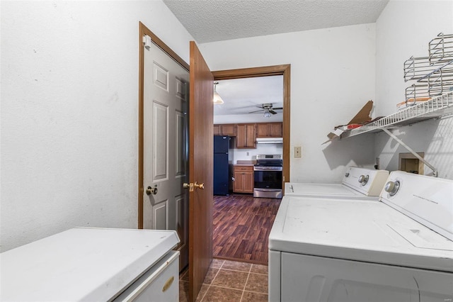 washroom with dark tile patterned floors, washing machine and clothes dryer, and a textured ceiling