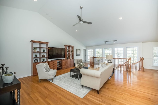 living room with vaulted ceiling, ceiling fan, and light wood-type flooring