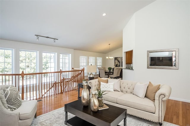 living room featuring lofted ceiling, a chandelier, and light hardwood / wood-style floors