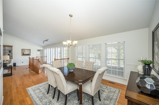 dining room featuring an inviting chandelier, vaulted ceiling, and light hardwood / wood-style floors