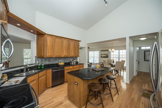 kitchen with high vaulted ceiling, stainless steel fridge, black dishwasher, and sink