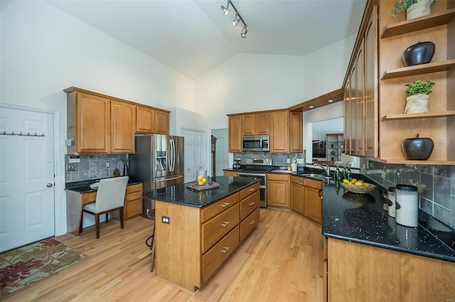 kitchen featuring sink, appliances with stainless steel finishes, high vaulted ceiling, a center island, and decorative backsplash