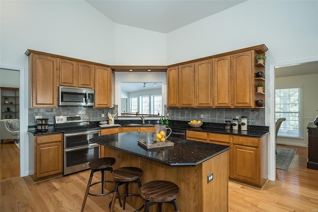 kitchen featuring sink, a center island, high vaulted ceiling, stainless steel appliances, and light hardwood / wood-style floors