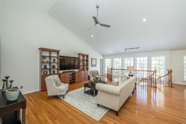 living room featuring light hardwood / wood-style flooring, ceiling fan, and vaulted ceiling