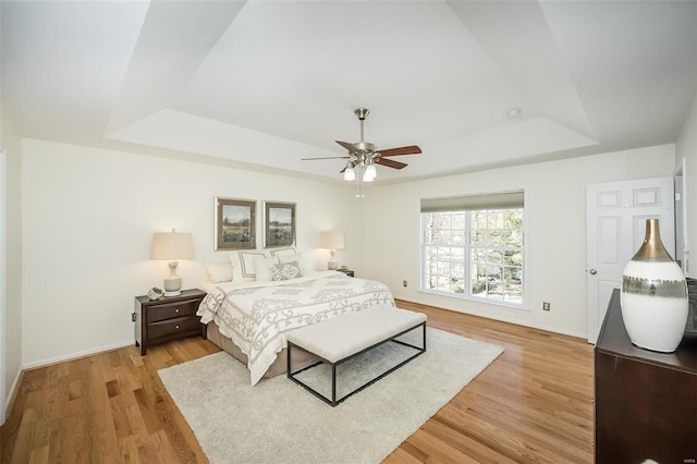 bedroom featuring a tray ceiling, light hardwood / wood-style floors, and ceiling fan