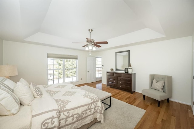 bedroom featuring hardwood / wood-style floors, ceiling fan, and a tray ceiling