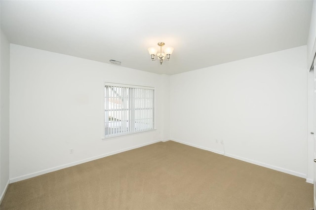 carpeted spare room with a chandelier