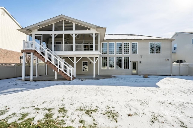 snow covered rear of property featuring a sunroom and ceiling fan