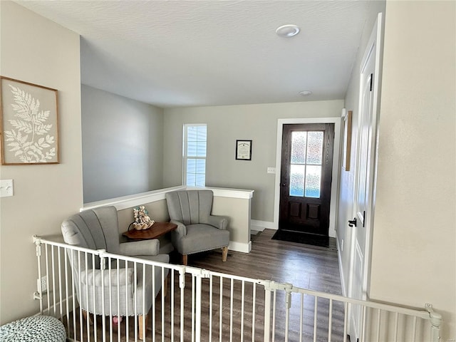 foyer entrance featuring a textured ceiling, baseboards, and dark wood-type flooring